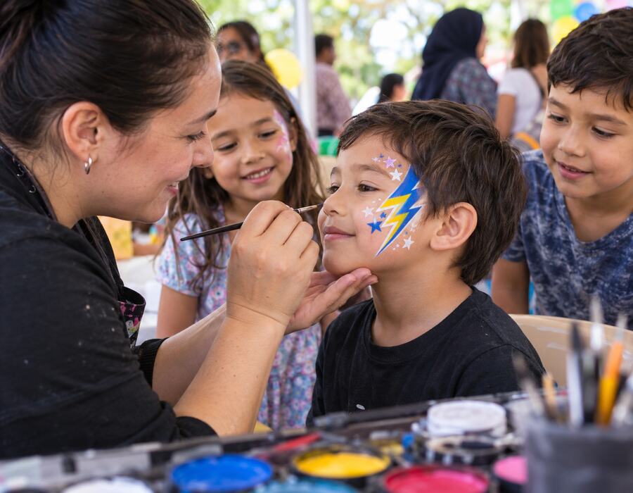 Children at a face paint party in a typical Logan setting. Use a real local photograph once